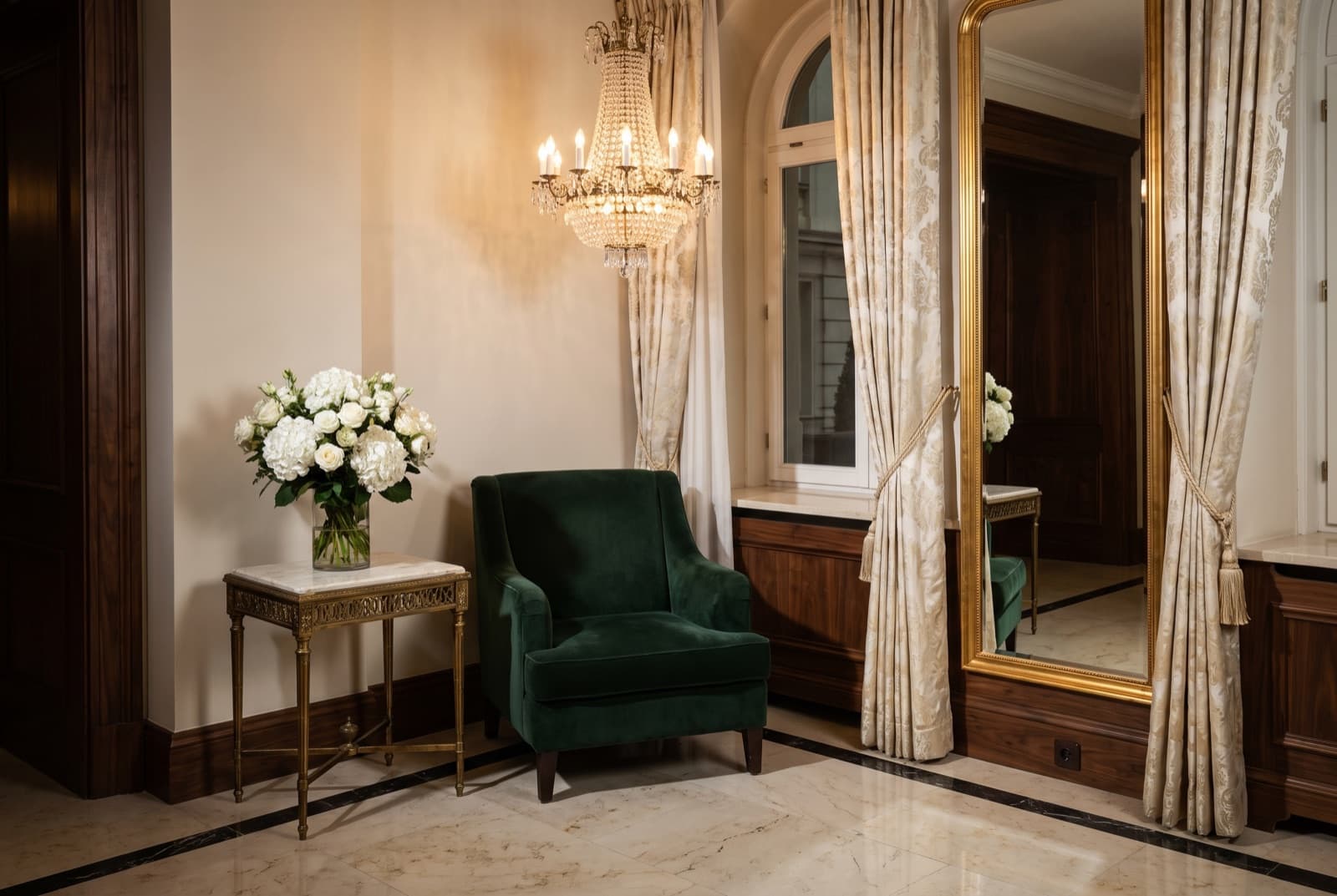 Otel lobisinde kemerli pencerenin yanında duran yeşil kadife koltuk.
